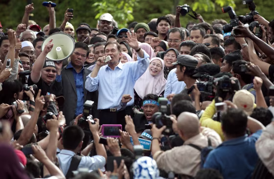 Image: Malaysian opposition leader Anwar Ibrahim  (C-L) speaks to his supporters as his wife Wan Azizah (C-R) smiles outside the court after his verdict in Kuala Lumpur.