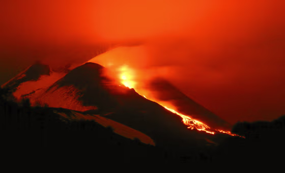 Italy's Mount Etna glows as lava pours down its flanks.