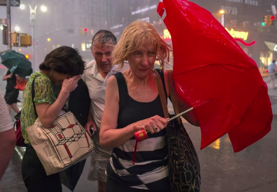 Image: Commuters dodge high wind and heavy rain during a thunderstorm in midtown Manhattan