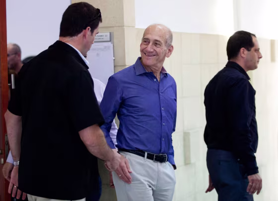Image: Former Israeli Prime Minister Olmert smiles as he leaves the court room after his hearing at the Jerusalem District court