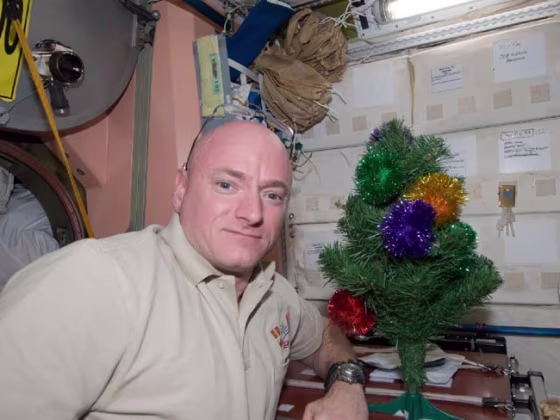 NASA astronaut Scott Kelly, commander of Expedition 26 aboard the International Space Station, poses for a holiday photo near the station's miniature Christmas tree in 2010.