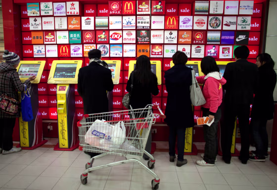 Image: People use a row of coupon machines near a supermarket entrance in Beijing, China
