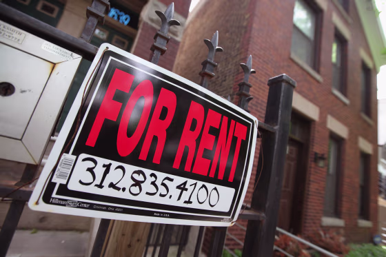 Image: A \"For Rent\" sign stands in front of a house