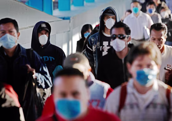 Image:  Passengers wearing face masks as a precaution against swine flu walk inside a metro station in Mexico City