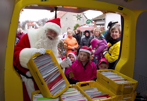 Image: A man dressed as Father Christmas carries crates with letters addressed to Santa Claus at special Christmas post office in village of Himmelpfort