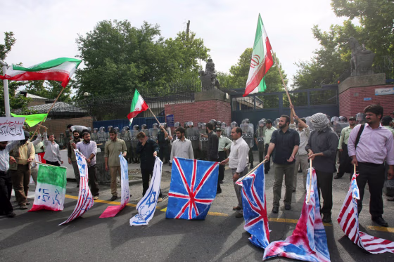 Supporters of Iran's government protest outside the British Embassy in Tehran on Tuesday,&nbsp;later burning the British, U.S. and Israeli flags.