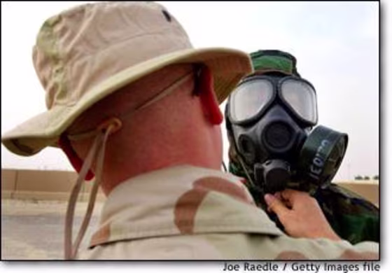 U.S. Marine Cpl. Dusty Mathews puts on a chemical protection suit and gas mask with help from Sgt. Darrin Minderman at Camp Commando in Kuwait on Dec. 3.