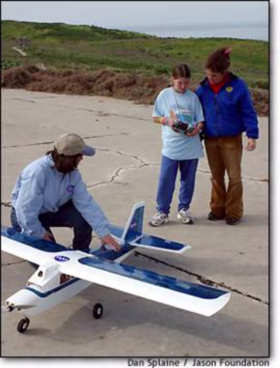 NASA education specialist Sallie Smith steadies one of NASA's experimental camera-equipped planes as student-researchers Rachel Sheppard and Gina Pambianchi go through a checklist.