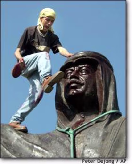 An Iraqi youth wearing a yellow bandana of the Kurdistan Democratic Party kicks the head of a statue of Saddam Hussein in Kirkuk on Thursday.