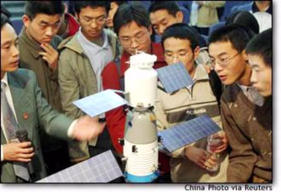 Chinese university students look at a model of the Shenzhou 5 spacecraft in Xian, the capital of China's central province of Shaanxi.