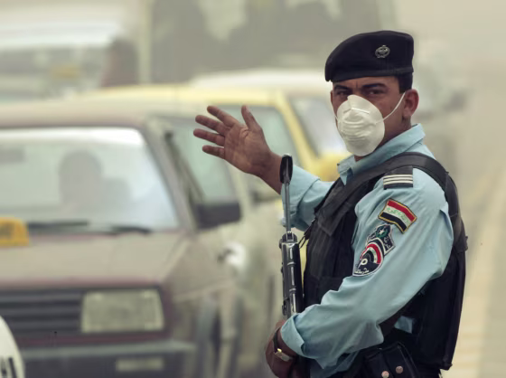Image:  policeman wears a mask as he directs traffic