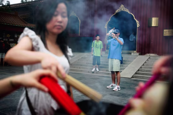 Image: A foreigner photographs Chinese faithful burning incense
