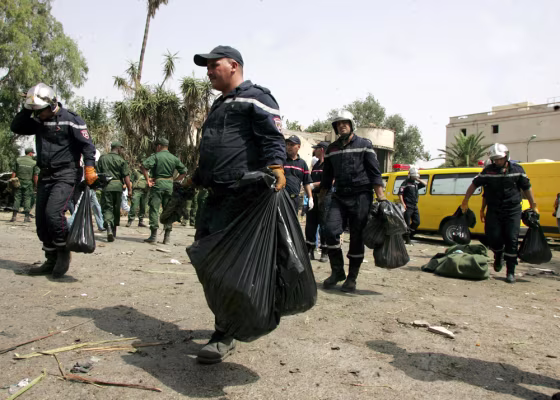 Image: Firemen carrying parts of human bodies killed in a car bomb attack near the National Gendarmerie school of Issers in the city of Boumerdes