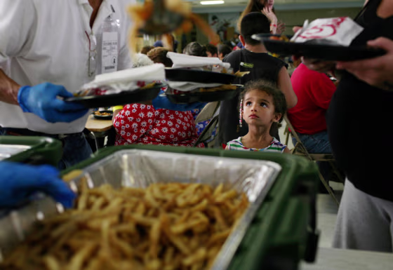 Hurricane Ike evacuee Nessa Devens, 4, of Corpus Christi, Texas, watches as a Red Cross volunteer serves dinner at a San Antonio Food Bank on&nbsp;Sept. 11.