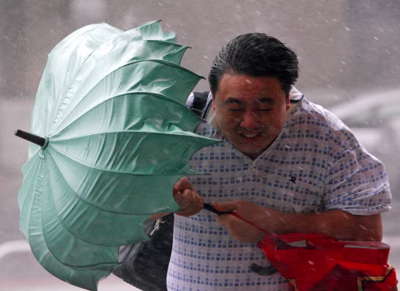 Image: Man struggles against wind with his umbrella as Typhoon Jangmi hits Taiwan