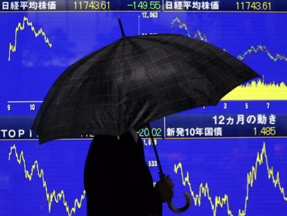 Image: A man strolls past a stock board outside a securities firm in Tokyo, Japan