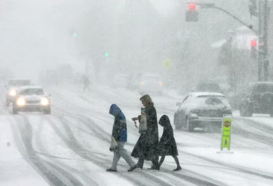 Pedestrians brave the blowing snow as they cross the main street of Chagrin Falls, Ohio on Sunday. 