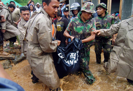Indonesian soldiers and volunteers wade through waters Wednesday&nbsp;as they remove a body following a landslide in Tawangmangu, on Java island.