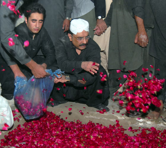 Image: Asif Ali Zardari (R) husband of former Pakistani premier Benazir Bhutto and his son Bilawal (L) shower rose petals on the grave of Bhutto