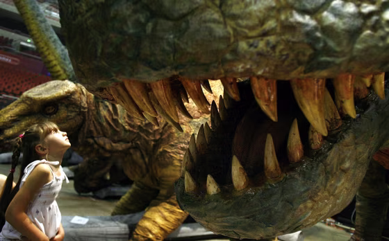 Image: Amy Hingerty, age five, looks into the jaws of an automated Tyrannosaurus Rex