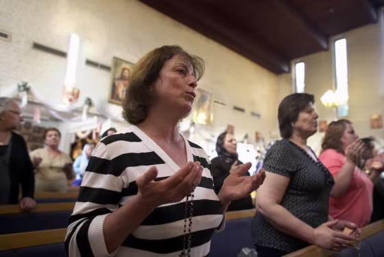 Nagiba Daud, front, prays at Johannes Church in Sodertalje, Sweden. The 52-year-old devout Christian fled Baghdad with her two sons after their family received death threats and their house was burned down.