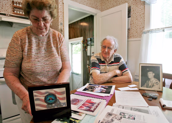 Mary Shostak opens a box containing a dog tag and class ring belonging to Felix Shostak as her husband, Charles, seated, looks on in Proctor, Vt.