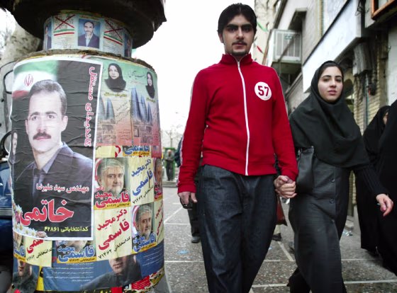 COUPLE WALK HAND IN HAND PAST CAMPAIGN POSTERS