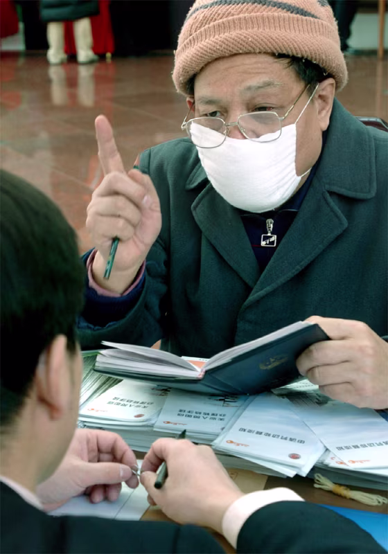 LOCAL REPRESENTATIVE OF THE NPC WEARS A MASK TO WARD OFF SARS IN BEIJING