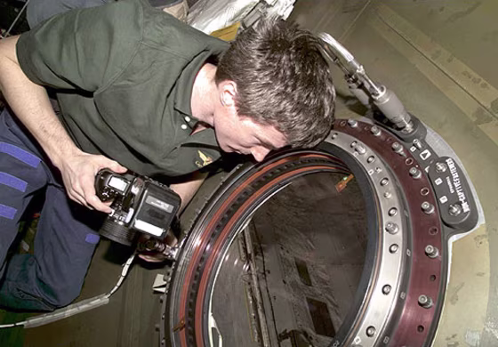 In a February 2001 photo, space station astronaut Sergei Krikalev peers out the Destiny module's optical-quality window. The U-shaped "flex hose" is visible above his head. 
