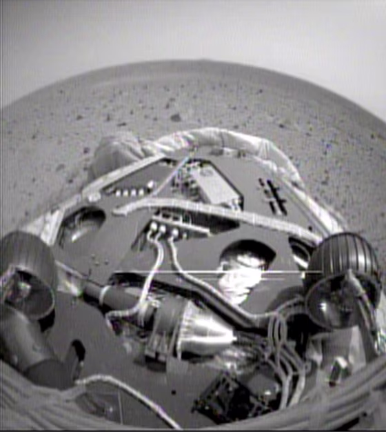 A fisheye view from one of the Spirit rover's navigation cameras shows the rover's front wheels, the front of its landing platform and the Martian landscape beyond. This shot was taken after Spirit backed up and executed a 45-degree turn on the platform.