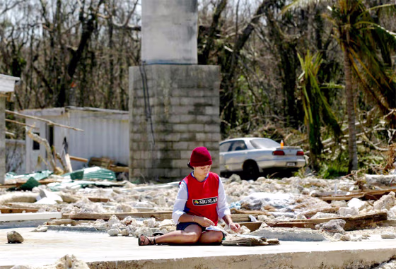 A RESIDENT OF THE ISLAND OF NIUE SITS AMONG THE REMAINS OF HER COUSIN'S HOME