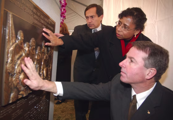 Sandy Anderson, the wife of Columbia astronaut Michael Anderson, passes her hand over the Columbia memorial at Arlington National Cemetery, flanked by astronauts Carlos Noriega on the left and Steve Robinson on the right.