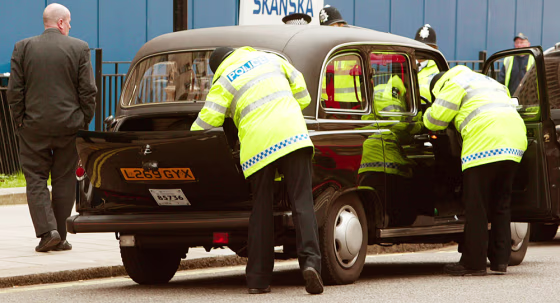 Police officers examine a taxi during a random stop and search operation in Westminster, London, on Wednesday, the day after London's police chief warned an "attack on London is inevitable." 