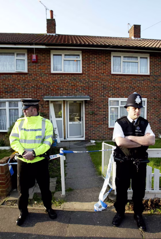 BRITISH POLICE OFFICERS STAND OUTSIDE A PROPERTY IN CRAWLEY FOLLOWING RAIDS