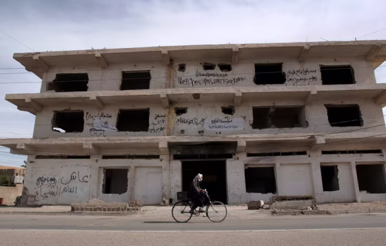 An Iraqi man&nbsp;cycles past a building previously used by U.S forces, and evacuated after several attacks, in Fallujah, west of Baghdad, on Thursday.