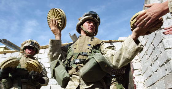 U.S. Marine Lcpl. Will McDermott passes anti-tank mines at an Iraqi insurgent weapons cache in Fallujah on Thursday.