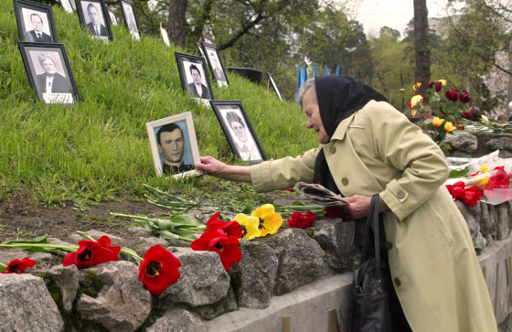 Praskoviya Nezhyvova places a photo of her son Viktor, who died following the Chernobyl clean-up, at the victims' monument in Kiev, Ukraine, on Monday.