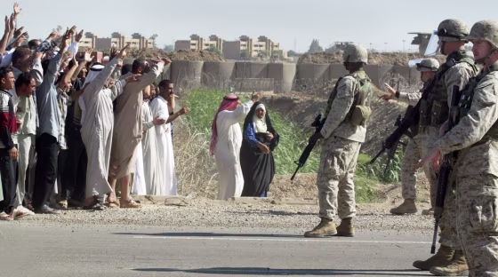Marines stop Iraqis from approaching a bus with 40 released detainees leaving the Abu Ghraib prison on Friday.