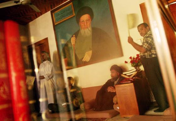 Sheik Ali Abdul-Careem Al-Madani (sitting on ground under a painting of his father),&nbsp;is in charge of a network of mosques in Baqubah. He listens to locals while being fanned. Electricity is scarce in Baquba.
