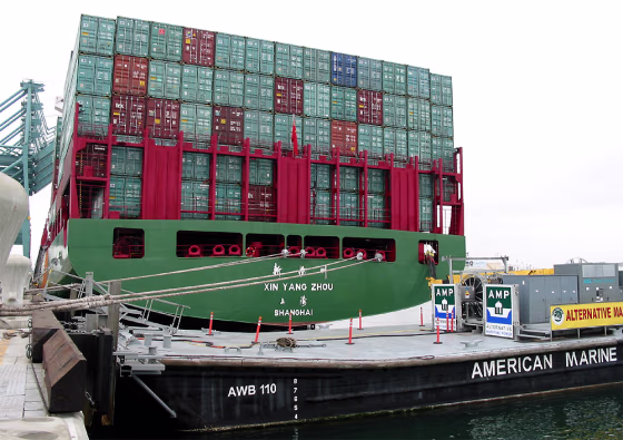 A container ship sits docked at the Port of Los Angeles Monday next to a barge carrying electrical equipment. Electrical power is routed from the barge to the ship so that it doesn't have to run its diesel engines while docked.