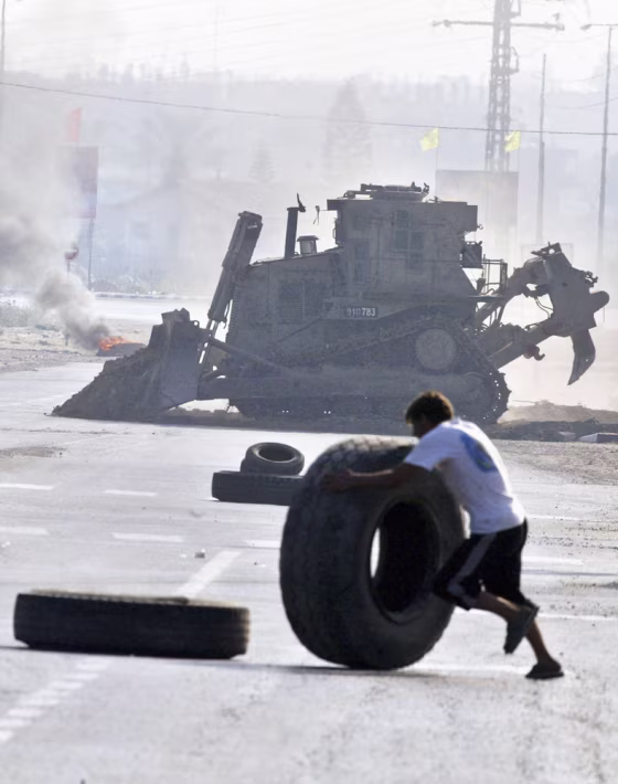 A Palestinian&nbsp;rolls a tire to erect a burning barricade to&nbsp;impede the advance of Israeli bulldozers and tanks Tuesday in the Gaza town of Beit Hanoun.&nbsp; 