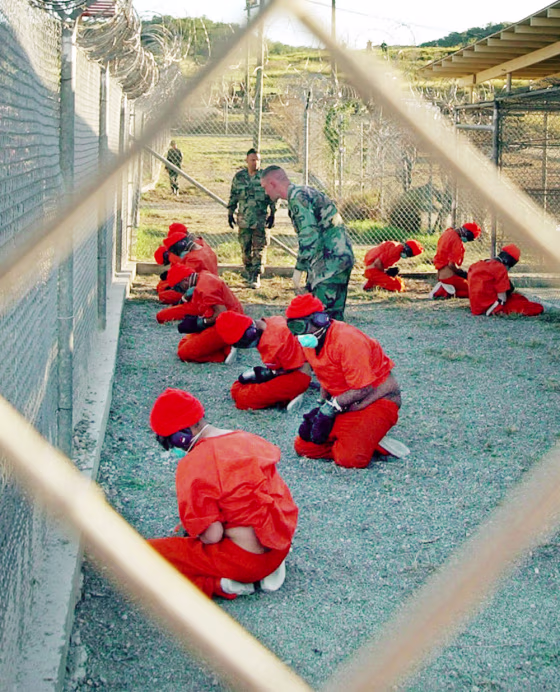 Alleged Taliban and al-Qaida detainees sit in a holding area at Camp X-Ray at Guantanamo Bay, Cuba, during in-processing to the temporary detention facility in this Jan. 11, 2002 file photo. 