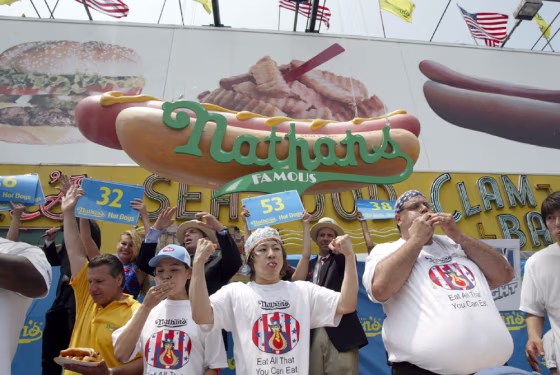 Takeru Kobayashi, center, of Nagano, Japan, holds his hands up in victory after winning the Nathan's Famous&nbsp;hot dog eating contest in New York on Sunday.