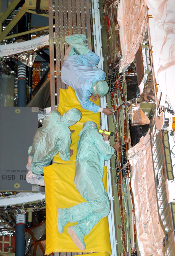 Workers check wiring during installation in the shuttle Discovery's cargo bay, in the Orbiter Processing Facility at NASA's Kennedy Space Center in Florida.
