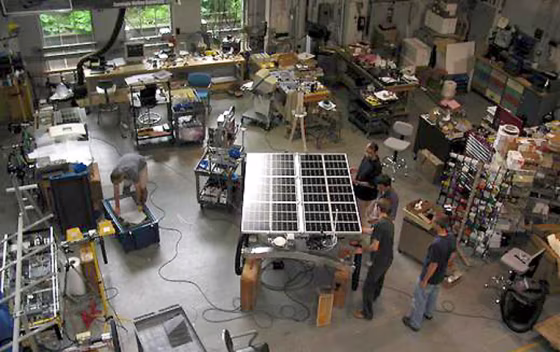 Researchers work on the solar-powered Zoë rover in the middle of a shop floor at Carnegie Mellon University.