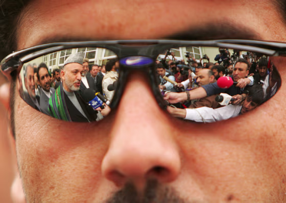 Afghan President Karzai is seen reflected in the sunglasses of a security guard in Kabul