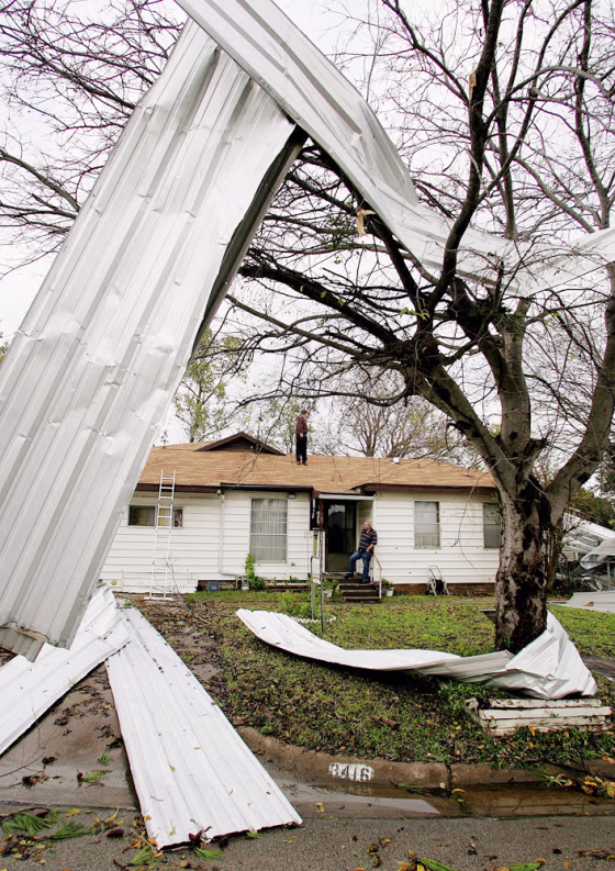 Sheets of corrugated steel are shown twisted in a tree and strewn around Johnny McCoy’s front yard in Grand Prairie, Texas, after severe weather ravaged the area Tuesday.