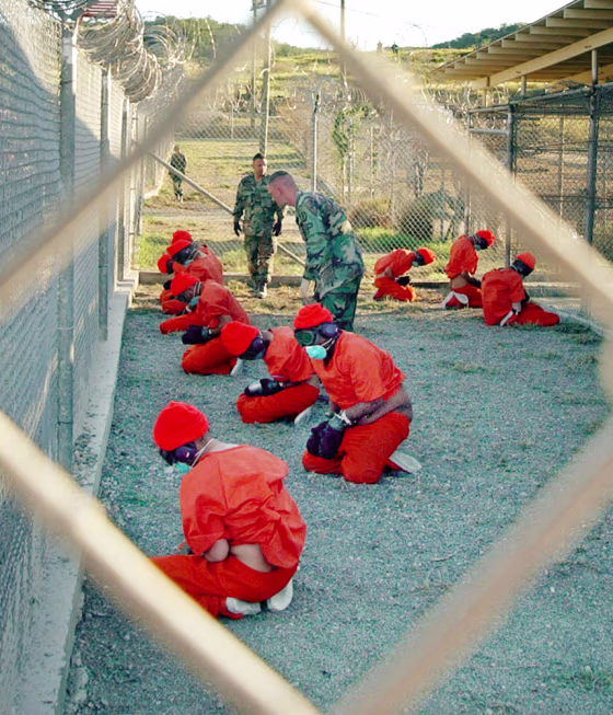Suspected Taliban and al-Qaida detainees sit in a holding area at Camp X-Ray at Guantanamo Bay, Cuba, in a Jan. 11, 2002, file photo. 