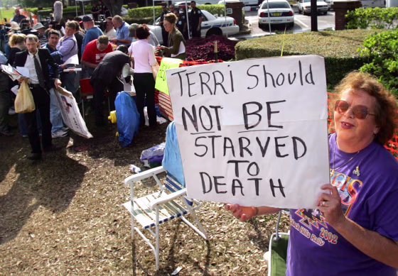 A supporter of  brain-damaged Florida woman Terri Schiavo holds poster in front of the the Woodside Hospice in Florida