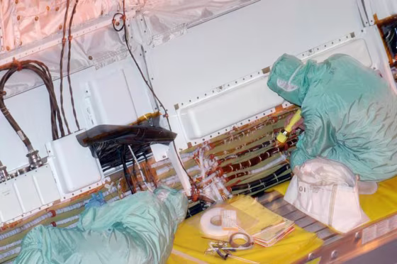 Inside Discovery's hangar at&nbsp;the Orbiter Processing Facility, workers remove wire tray covers on Discovery and add extra padding on Friday.